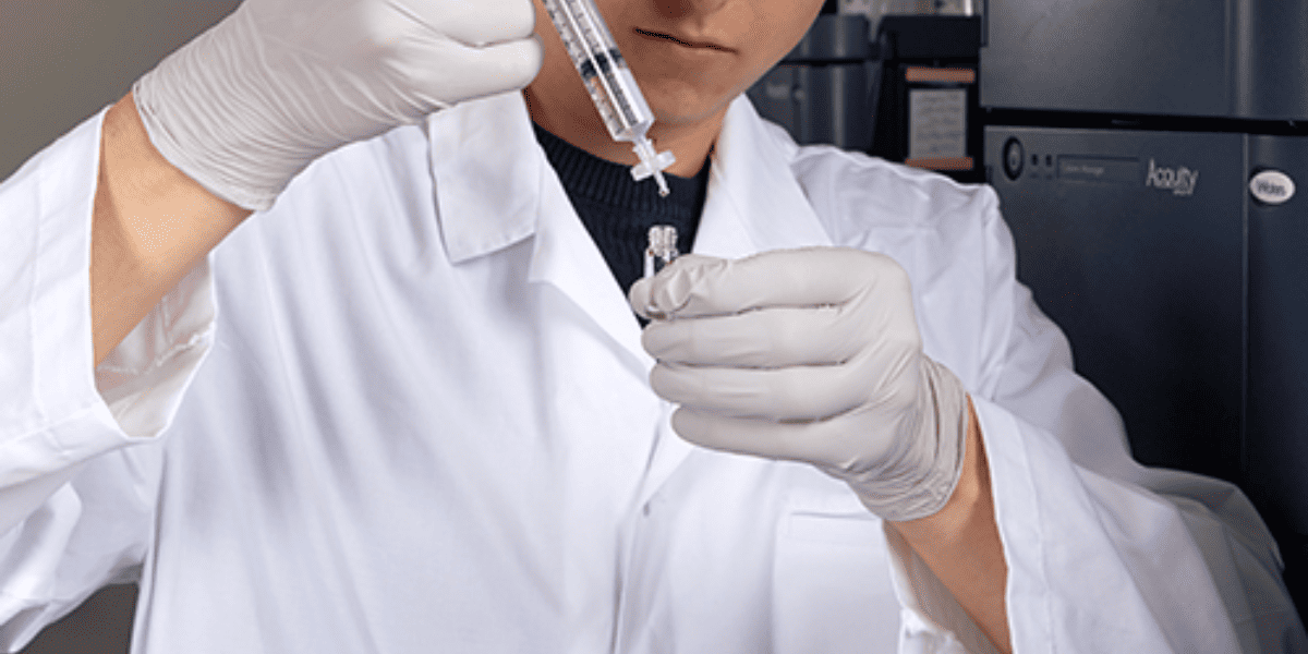 scientist-filtering-sample-through-syringe-filter-under-laminar-flow-hood.png
